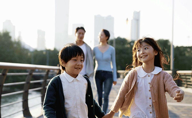 Dos hermanos sonrientes caminando delante de sus padres