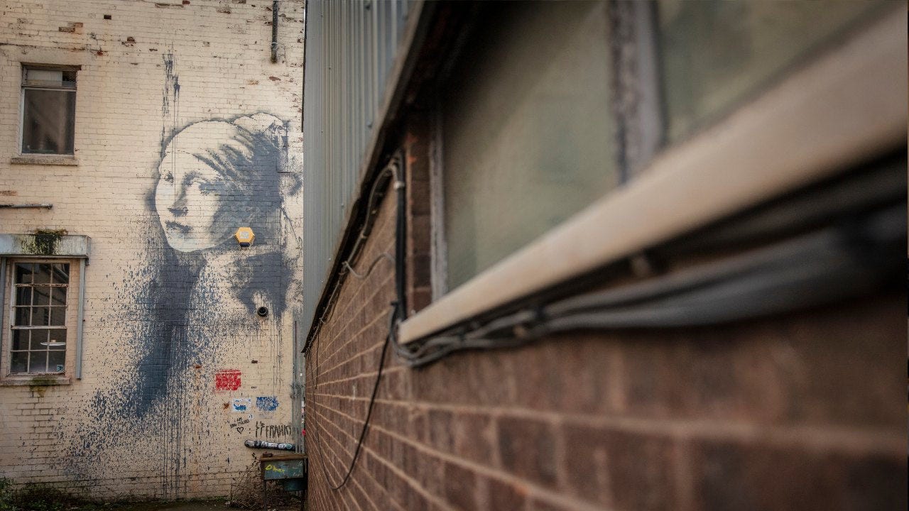 El mural de Banksy de 2014 "Girl With a Pierced Eardrum" en un callejón de Bristol se inspiró en el Vermeer, pero con el pendiente de perla reemplazado por una alarma de seguridad amarilla. 