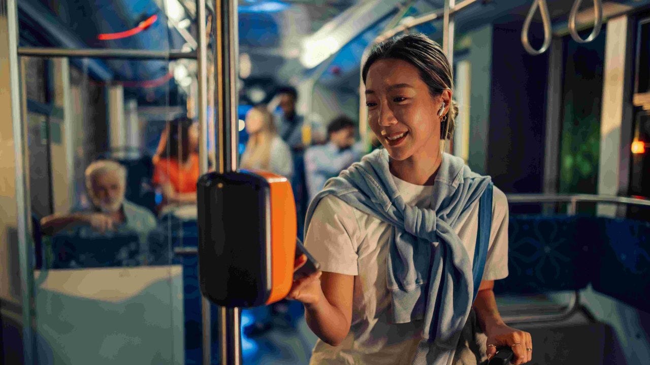 Young woman paying bus fare with contactless payment on public transport