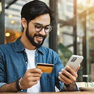 رجل ينظر إلى الهاتف ويحمل بطاقة إئتمان. 