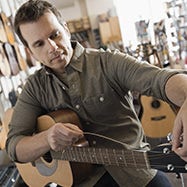 Hombre reemplazando cuerdas en una guitarra.