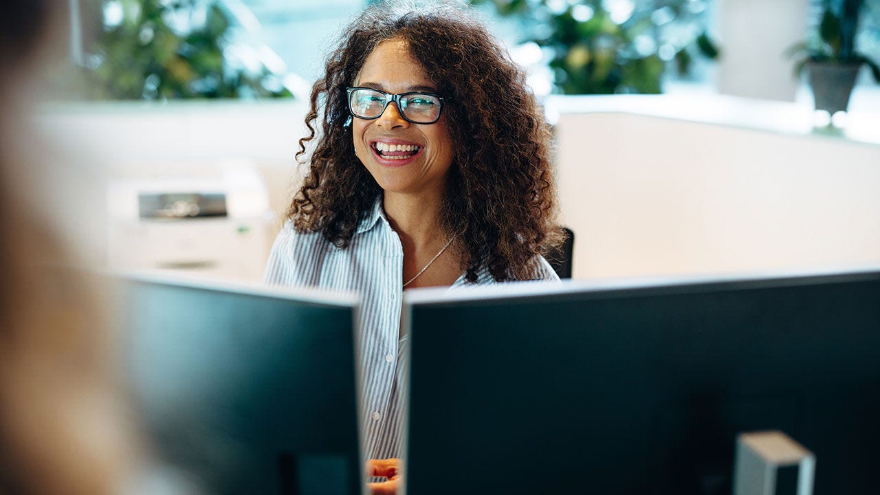 Woman poking head out of a cubicle in an office.