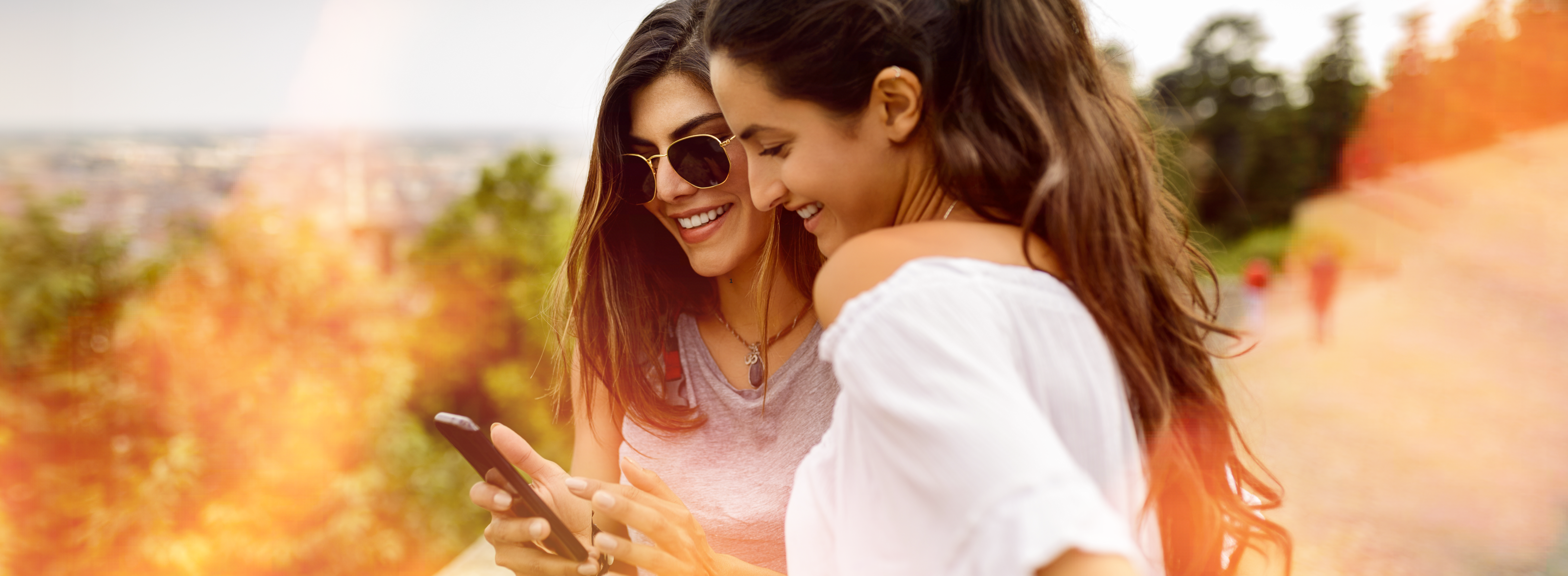 Dos mujeres sonriendo mientras navegan en sus teléfonos