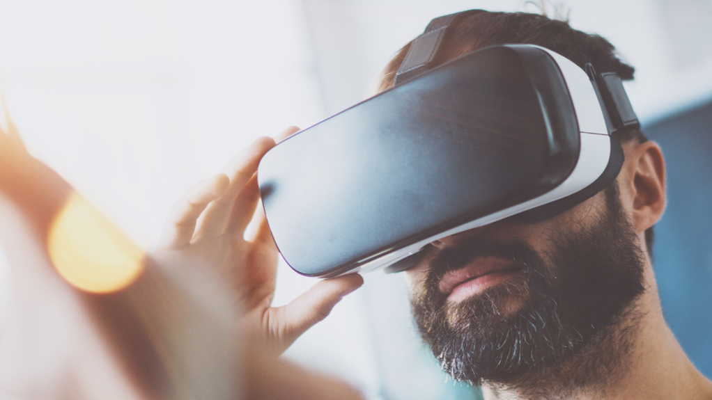 Un hombre con gafas de realidad virtual extiende una mano. 