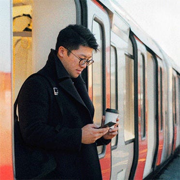 Hombre mirando el teléfono en la estación de tren.