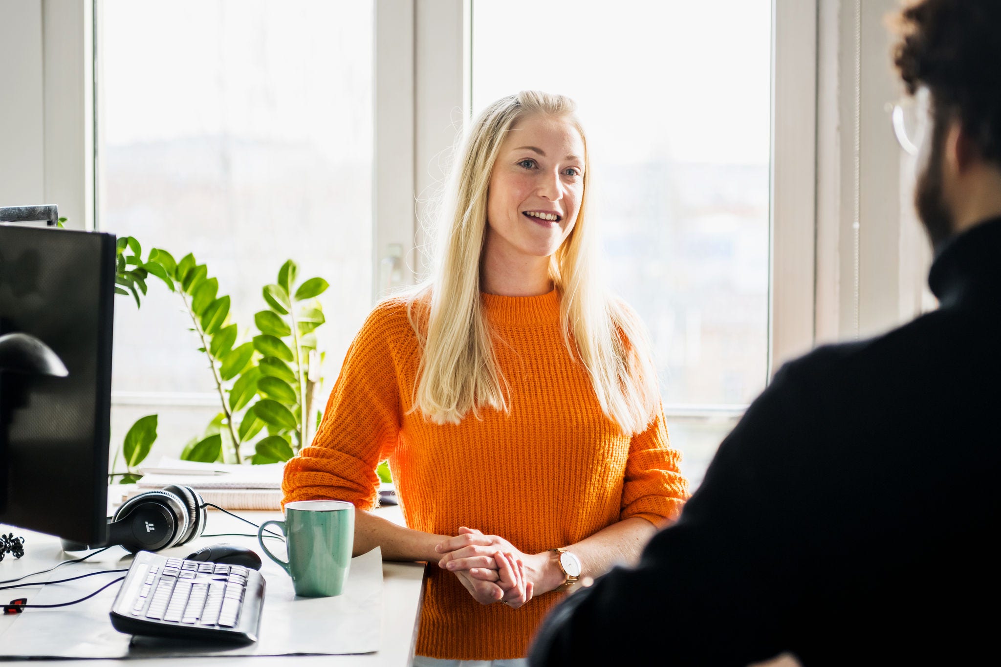 A woman taking with her teammate on monitor desk