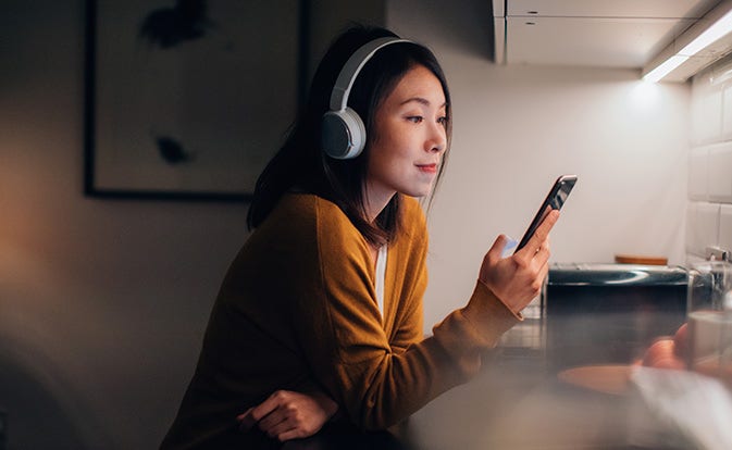 woman wearing headphones and using phone.
