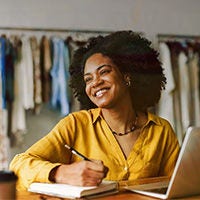 Joven sonriendo mientras trabaja en la computadora