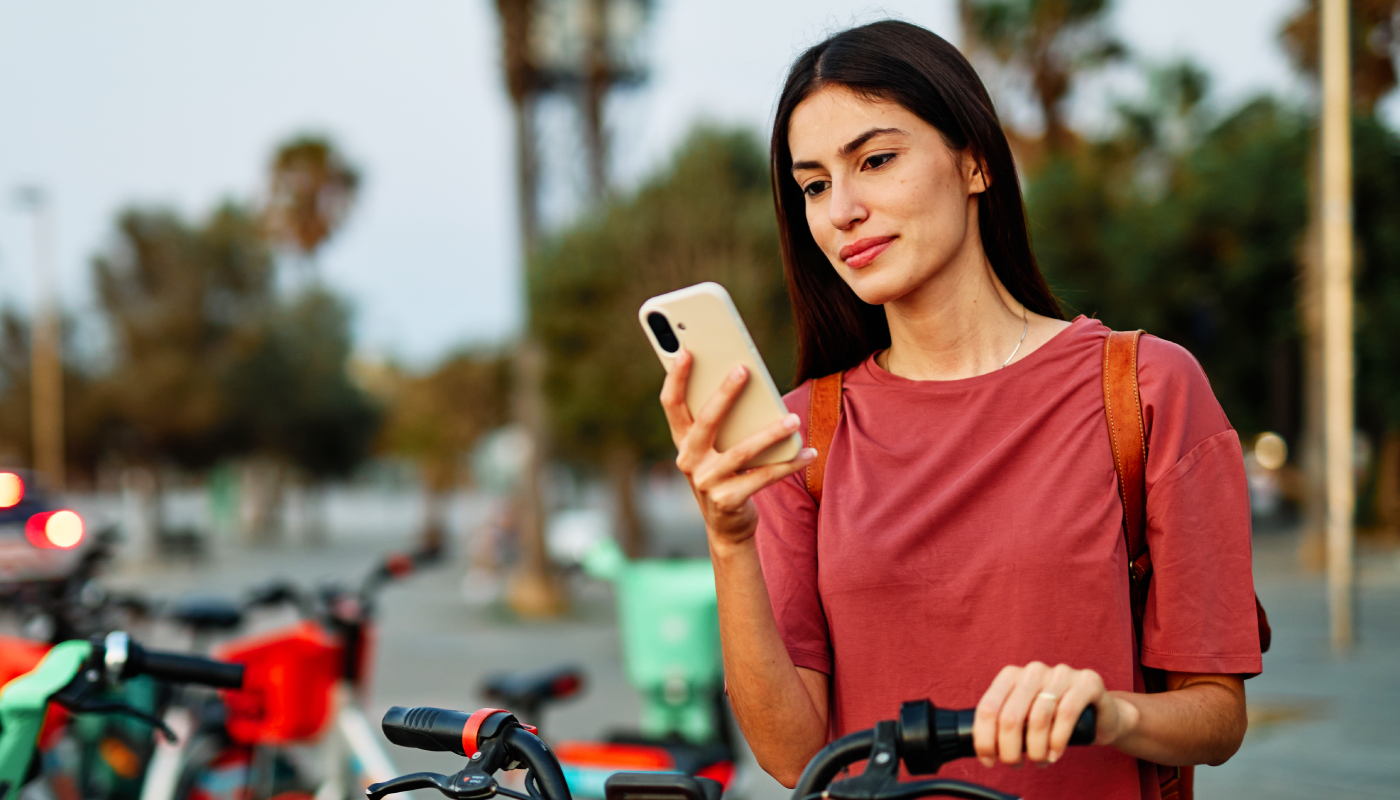 Woman on her phone before taking her bike on a work commute