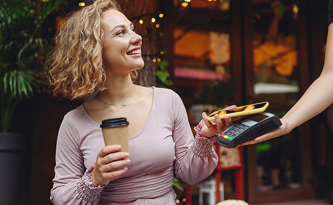 mujer pagando café con su teléfono.