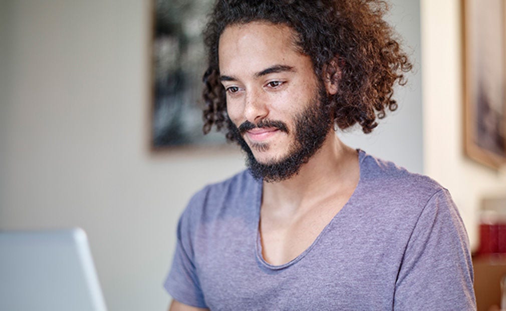 Jeune homme barbu utilisant un ordinateur portable