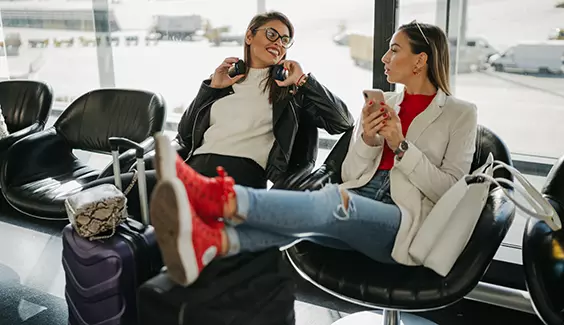 Women talking while waiting at a boarding gate
