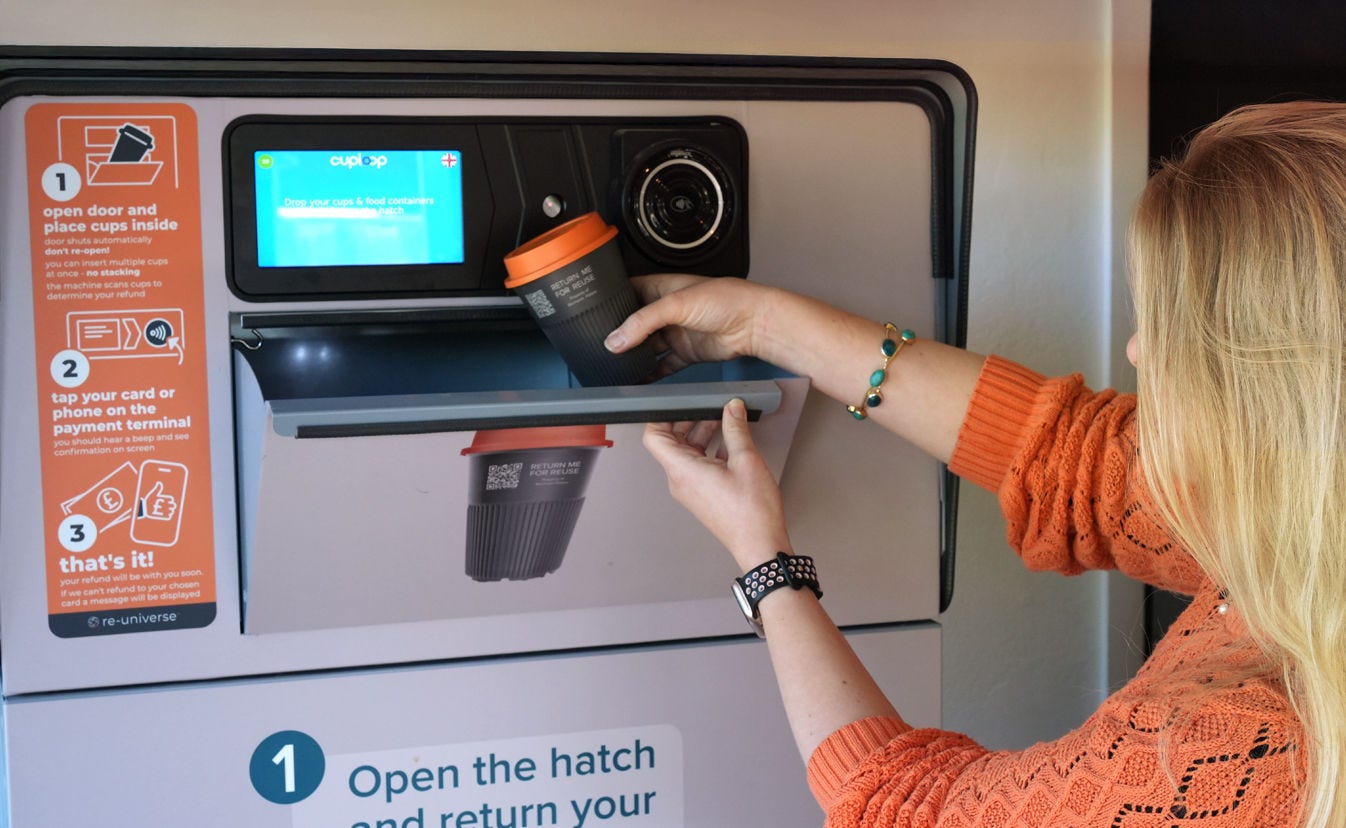 Mujer arrojando vaso de papel en máquina de reciclaje