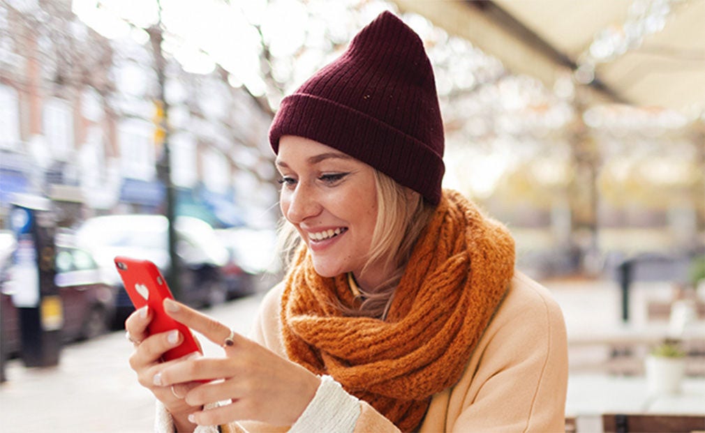 Femme portant un chapeau, utilisant son téléphone.