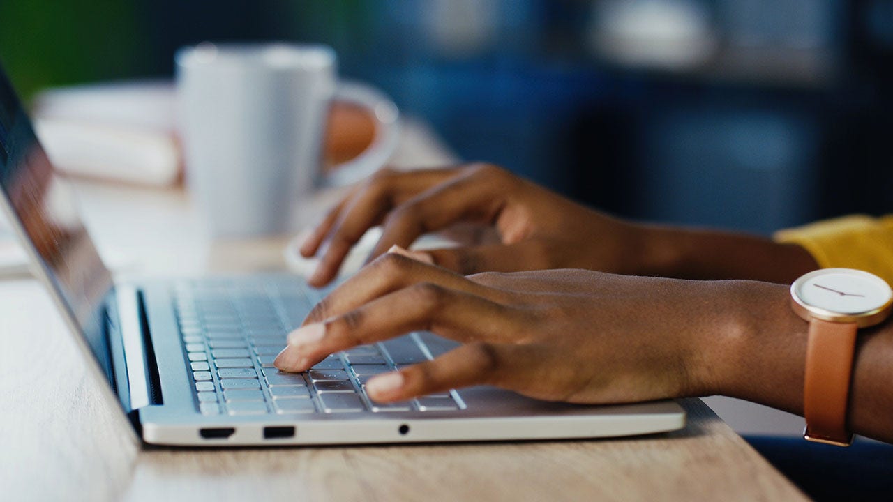 Manos femeninas escribiendo en una computadora portátil.