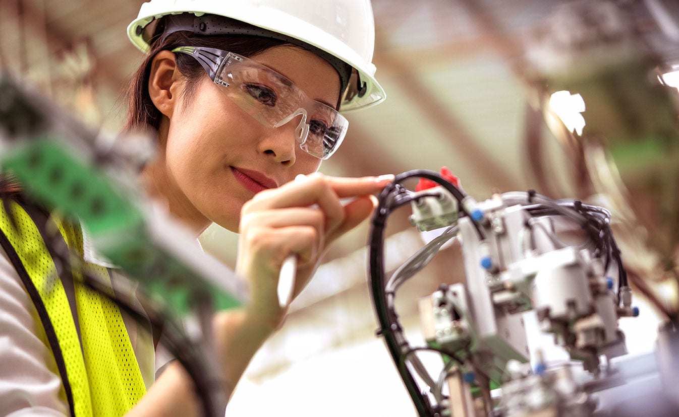 Mujer usando casco de protección y gafas de seguridad trabajando en una máquina