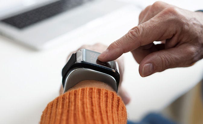 Une personne tape sur sa montre connectée pour examiner les détails de la transaction.