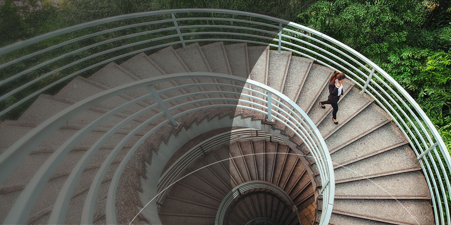 Una persona desciende por una escalera de caracol, mostrando las elegantes curvas de la escalera y la arquitectura circundante.