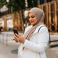 Woman with head scarf looking at phone.