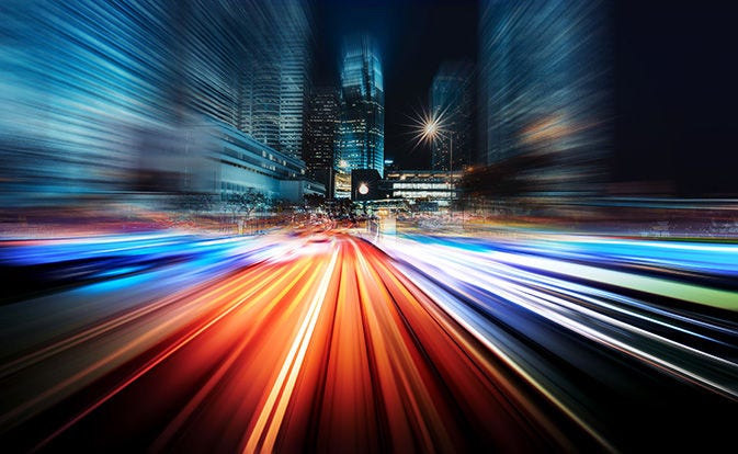 Abstract city lights with colorful motion blur streaking down a road at night.