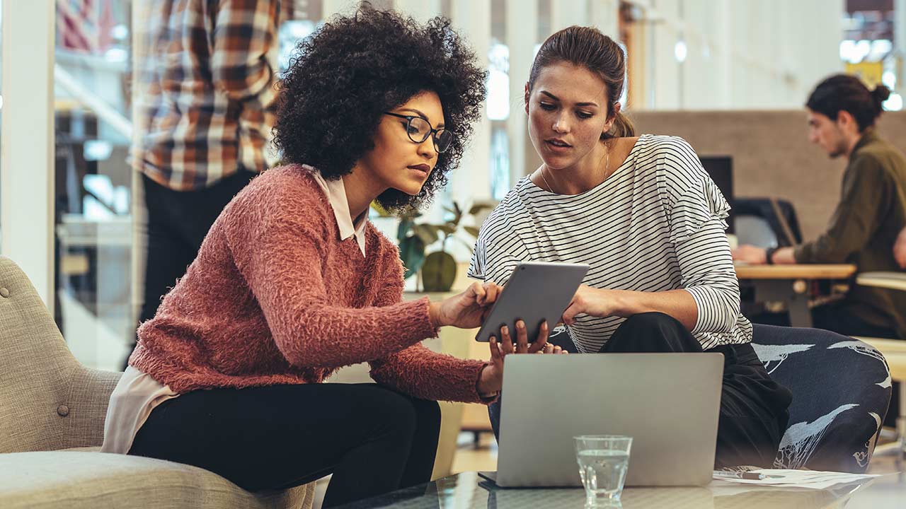 Des collaboratrices discutent de leur travail dans un bureau moderne.