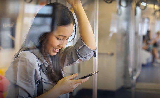 Mujer mirando el teléfono mientras viaja en transporte público.