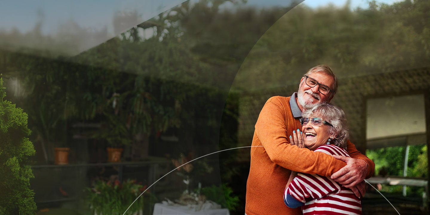 Una pareja de ancianos feliz se abraza en el patio.