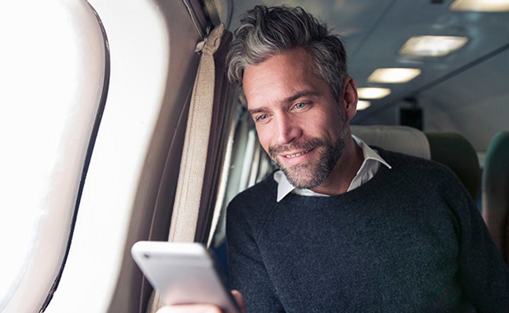 Man looking at phone while on the plane