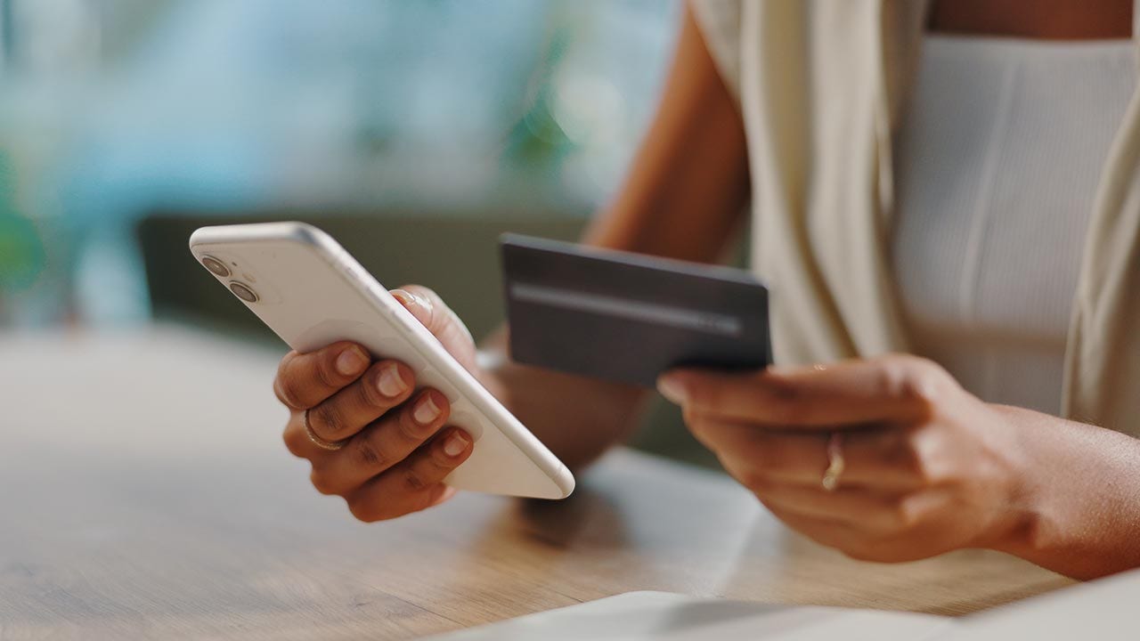 Tenant son téléphone et sa carte de crédit.