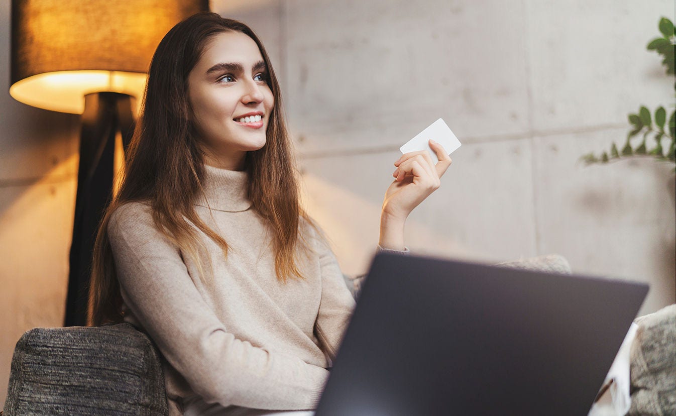 Una mujer sentada en un sofá sosteniendo una tarjeta en una mano.