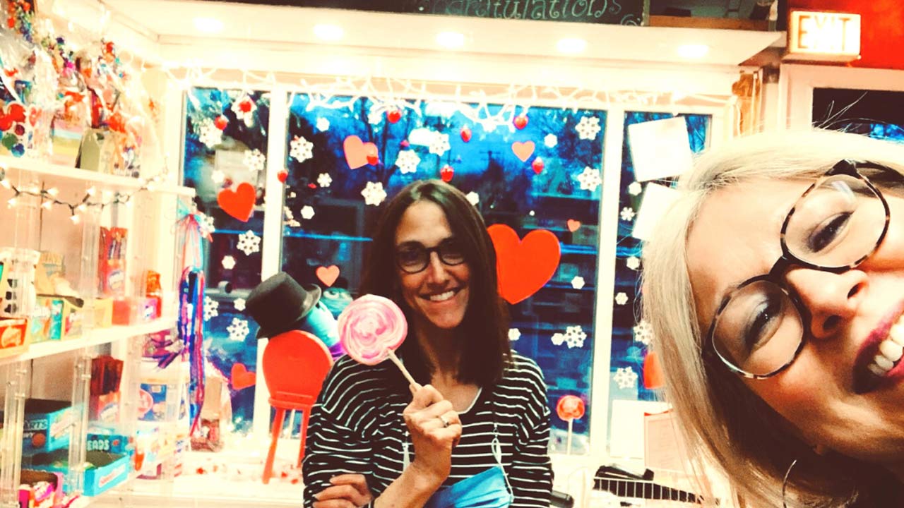 Mujer sosteniendo una gran piruleta en una tienda de dulces.