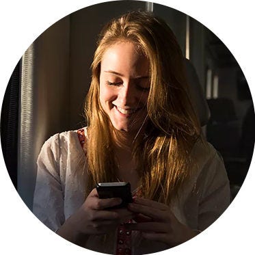 Mujer sonriendo y mirando su teléfono.