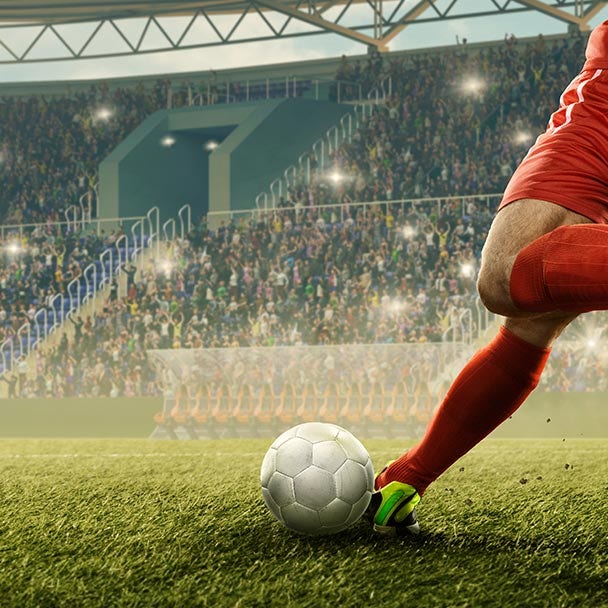 Persona pateando una pelota de fútbol en un juego profesional.