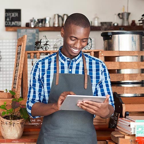 Shop owner checking his profit on a tablet.