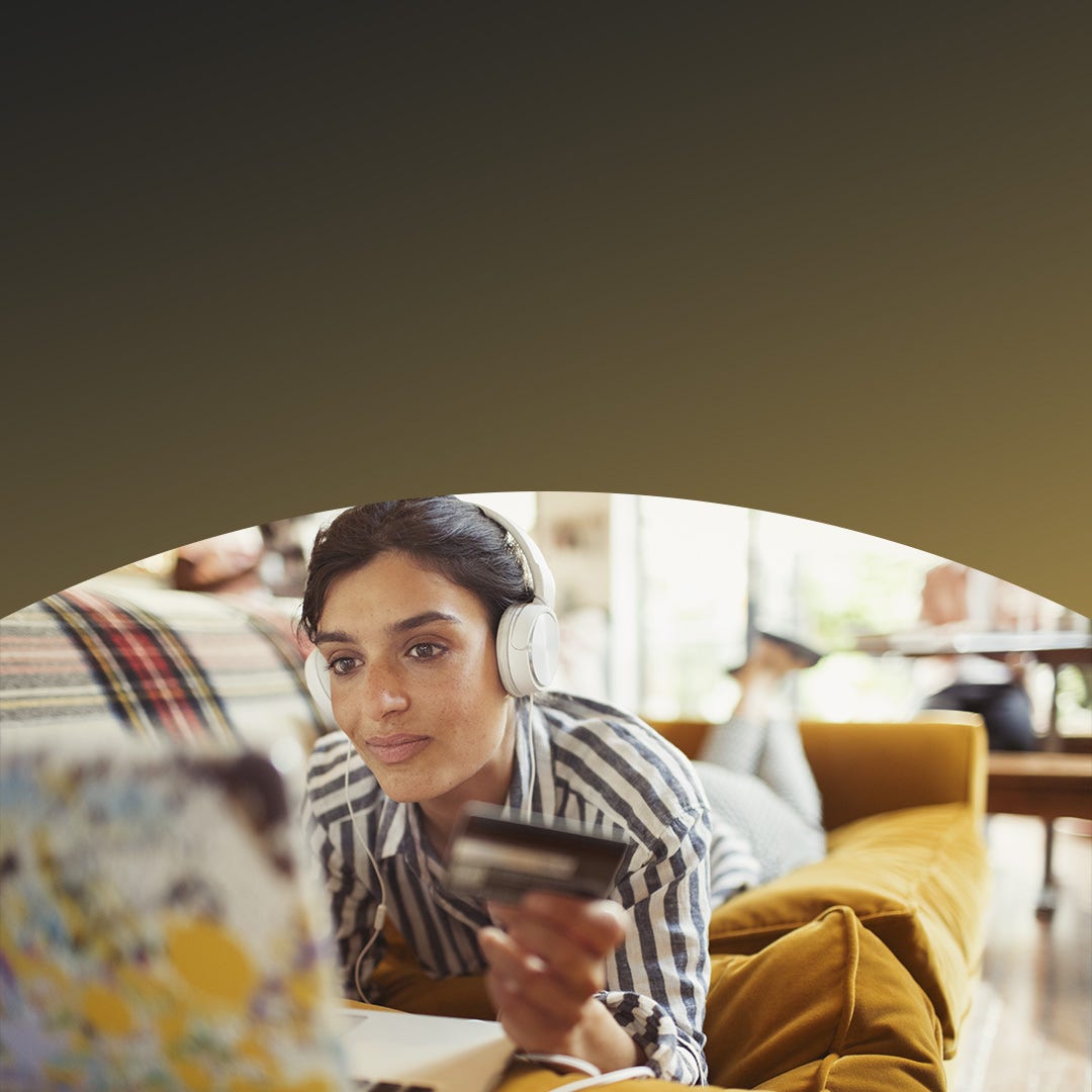 Jeune cliente avec une carte de crédit à la main portant des écouteurs