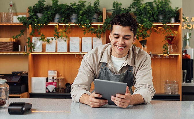 Dueño de una cafetería en el mostrador con una tableta digital.
