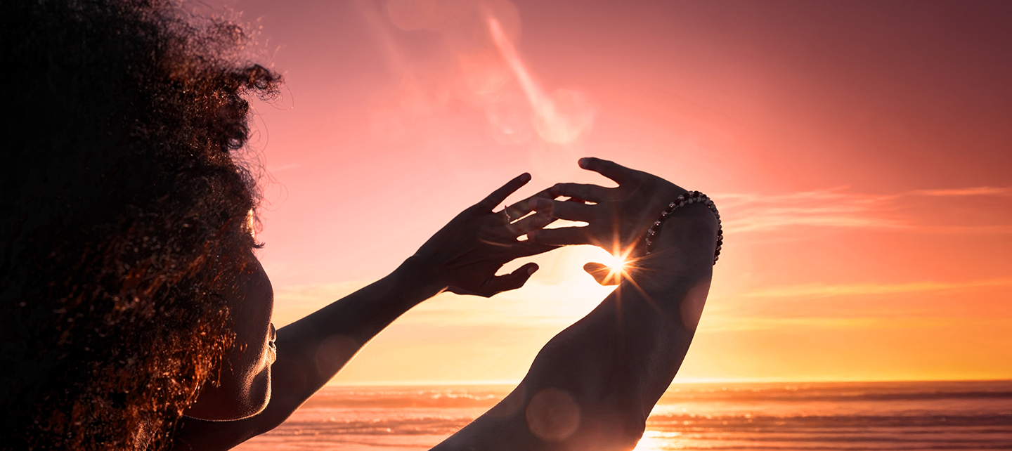 Une femme encadre le soleil avec ses mains