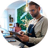 Un petit commerçant derrière un comptoir qui regarde une tablette