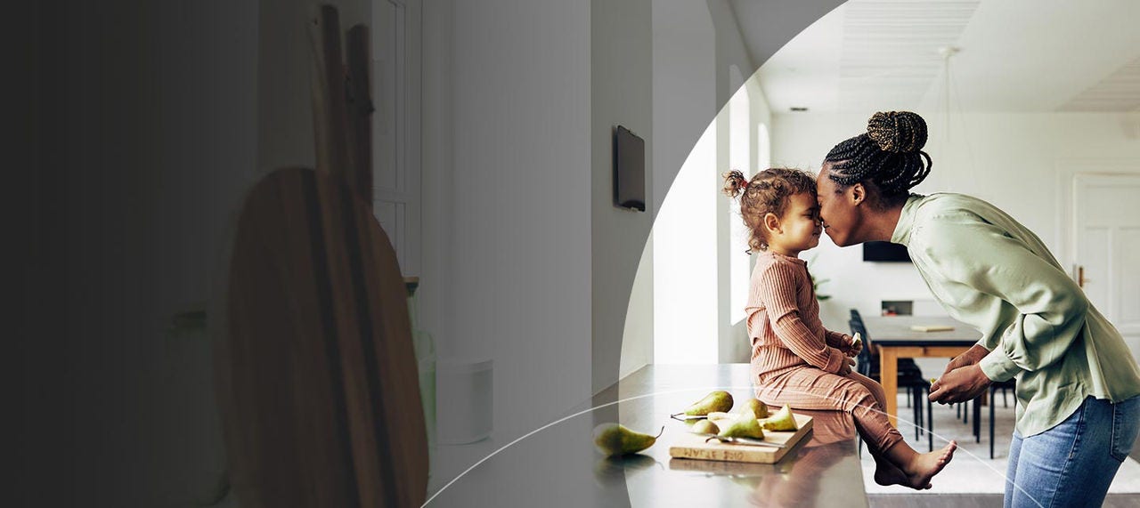 Mum touching heads with daughter in kitchen.