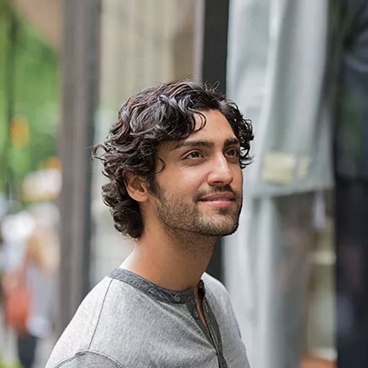 Man smiling outdoors in a city setting.