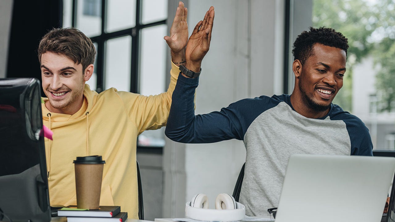 Des programmeurs se tapant dans la main alors qu’ils travaillent ensemble au bureau.