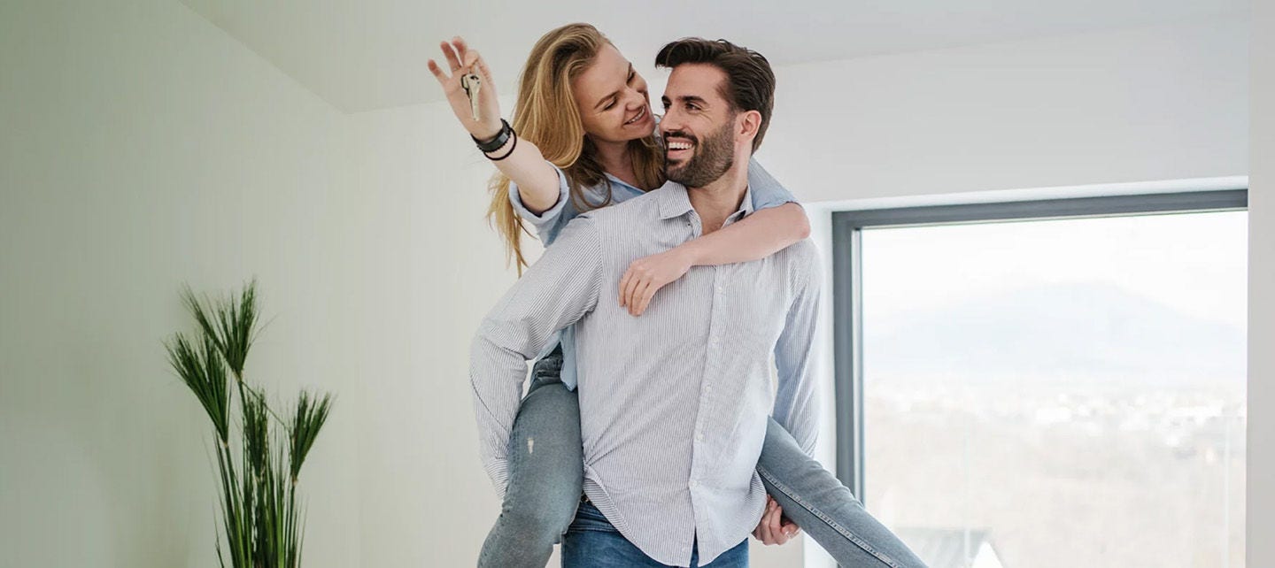 Un homme et une femme heureux d'entrer dans leur nouvelle maison avec les clés après avoir obtenu un prêt hypothécaire.