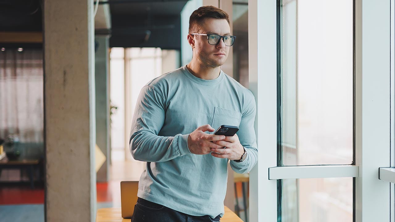 Homme regardant par la fenêtre avec inquiétude.