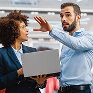 Empresaria usa una computadora portátil mientras habla con un colega.