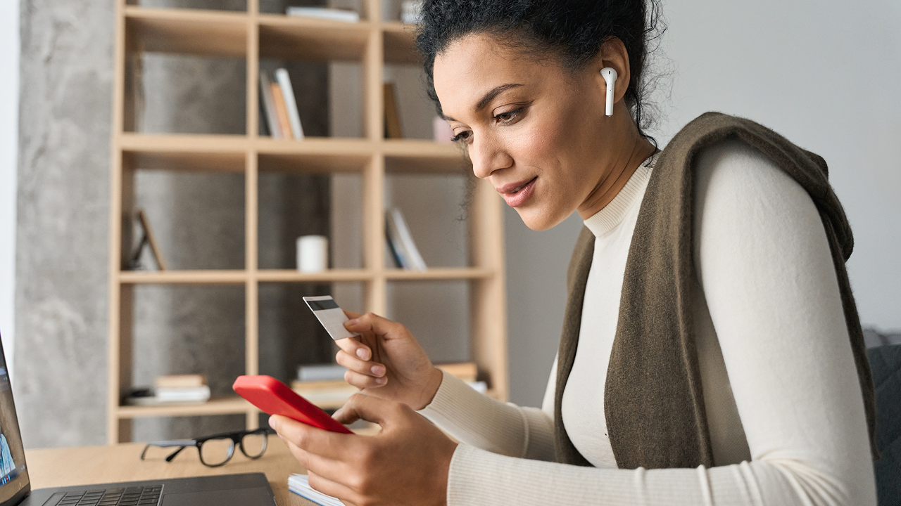 A woman sitting at a desk using a cell phone wearing earpod