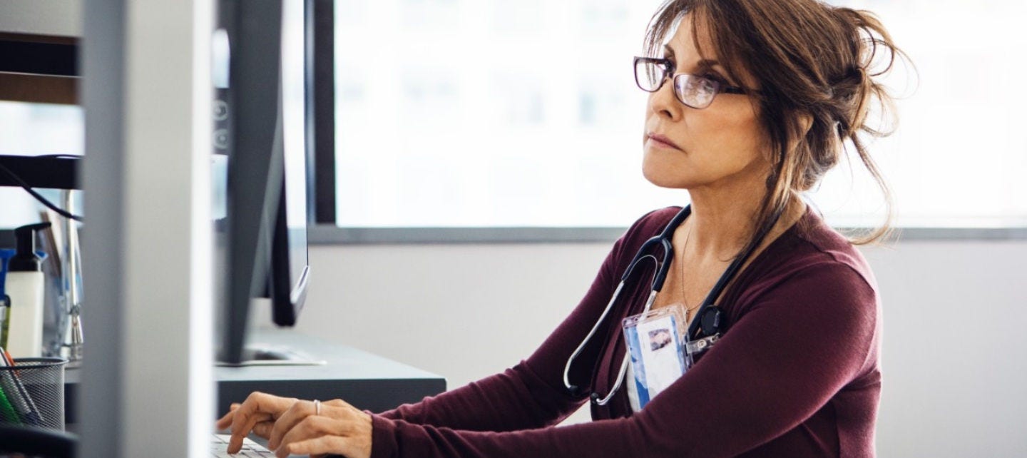 A doctor looks at a computer screen. 