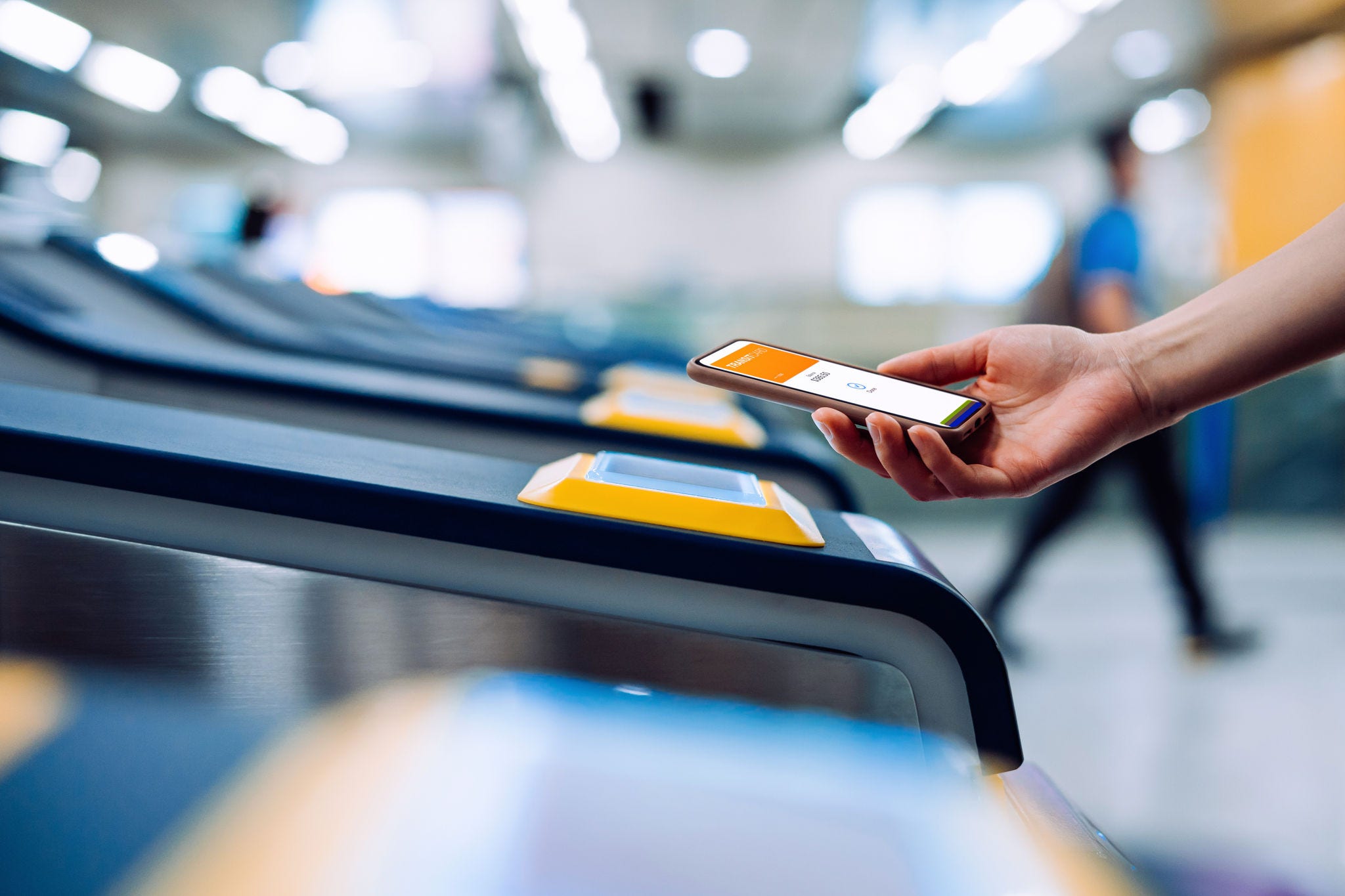 Persona tocando el teléfono en la terminal de acceso a la estación del metro.