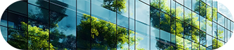 Un bâtiment moderne avec de grandes fenêtres reflétant les arbres environnants dans un ciel bleu clair.
