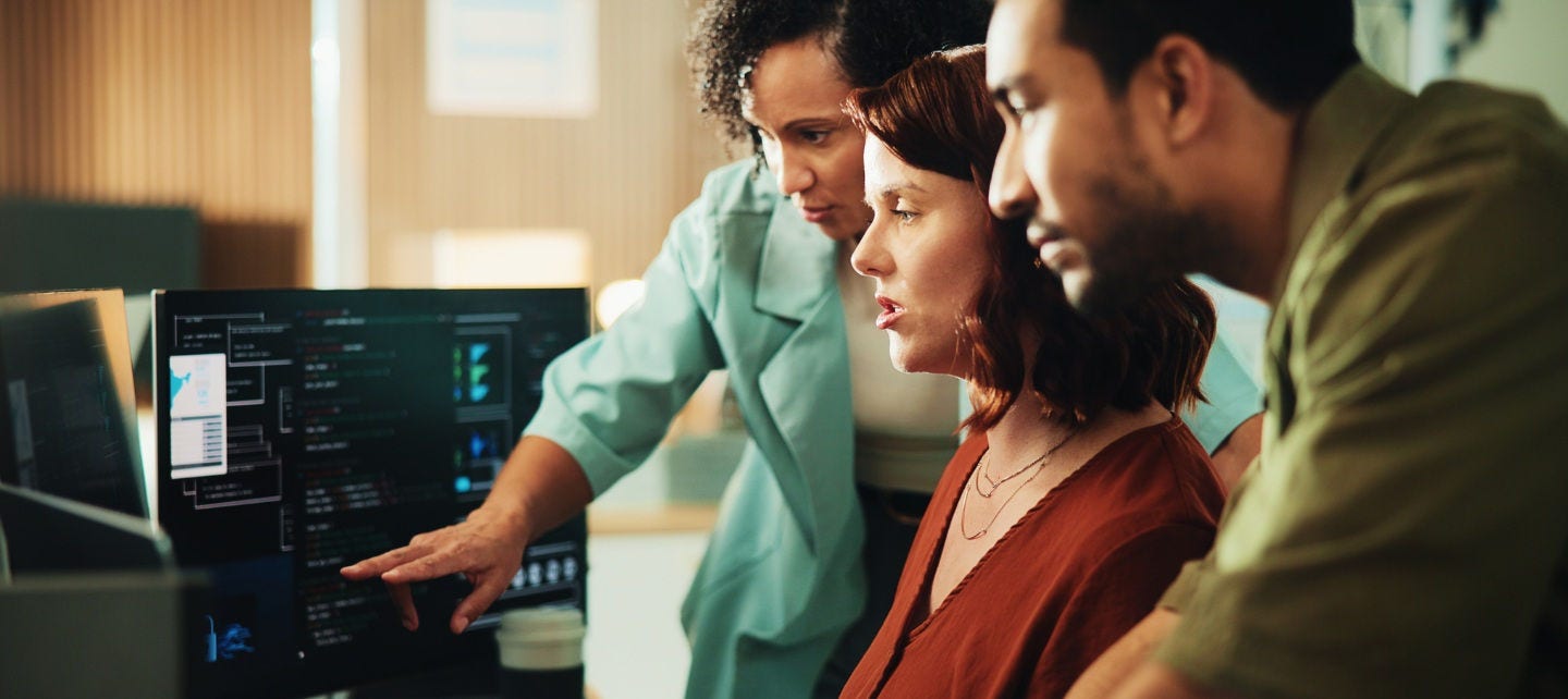 Three professional people look seriously at a computer. 