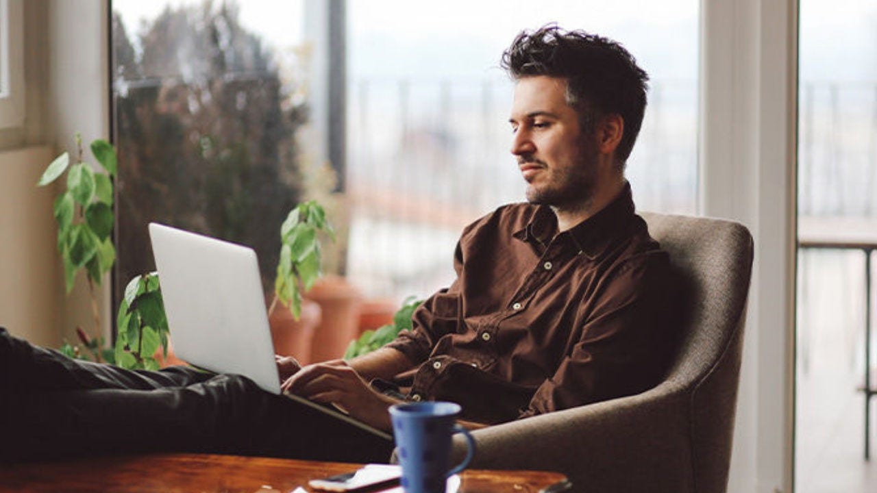 A man looks at his laptop in a living room. 